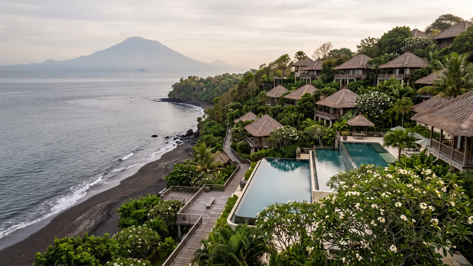 Hillside resort with tiered pools above a black-sand beach in east Bali